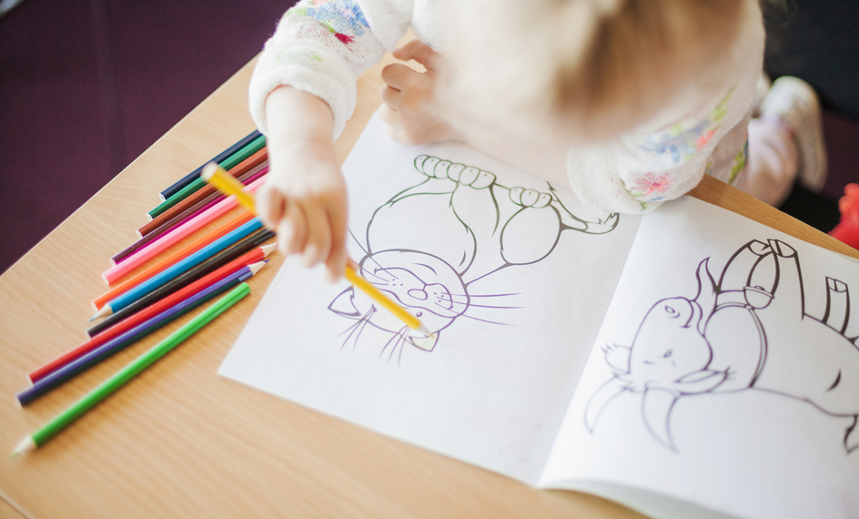 girl-holding-pencil-sitting-table